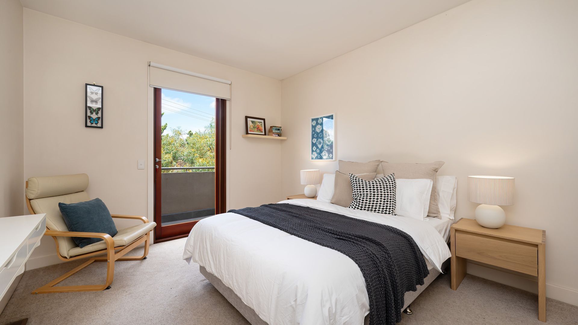 A bedroom with a bed, a chair, a nightstand, and a window with a view of trees.