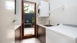 Eine kompakte Küche mit integrierter Waschmaschine und Trockner, einem kleinen Spülbecken und einer Tür zu einer Terrasse mit Blumentöpfen.