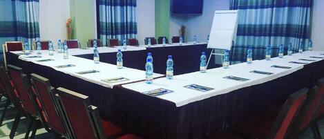 A conference room with a long table, red chairs, water bottles, and a whiteboard.