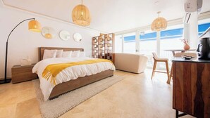 A modern bedroom with a large bed, bedside tables, a wooden desk, and a bookshelf.