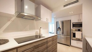 Una cocina moderna con electrodomésticos de acero inoxidable, armarios de madera y una placa de cocción de vidrio.