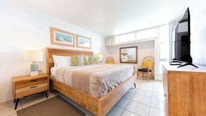 Un dormitorio con una cama de madera, mesitas de noche, un escritorio y una televisión.