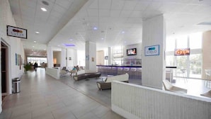 Un lobby amplio con mostrador de recepción, zona de estar y una pantalla de televisión.