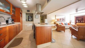 A modern kitchen with wooden cabinets, a central island, and a dining area with wicker furniture.