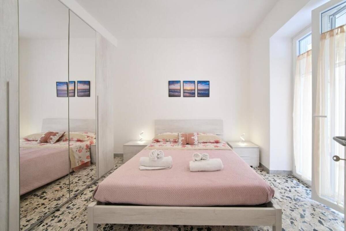 A bedroom with a bed, bedside tables, a mirror, and artwork on the wall.