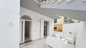 A modern, clean hotel lobby with a reception desk, seating area, and a staircase leading to an upper level. - Casa Lulù (Ischia)