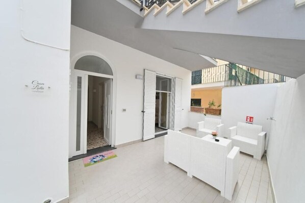A modern, clean hotel lobby with a reception desk, seating area, and a staircase leading to an upper level.