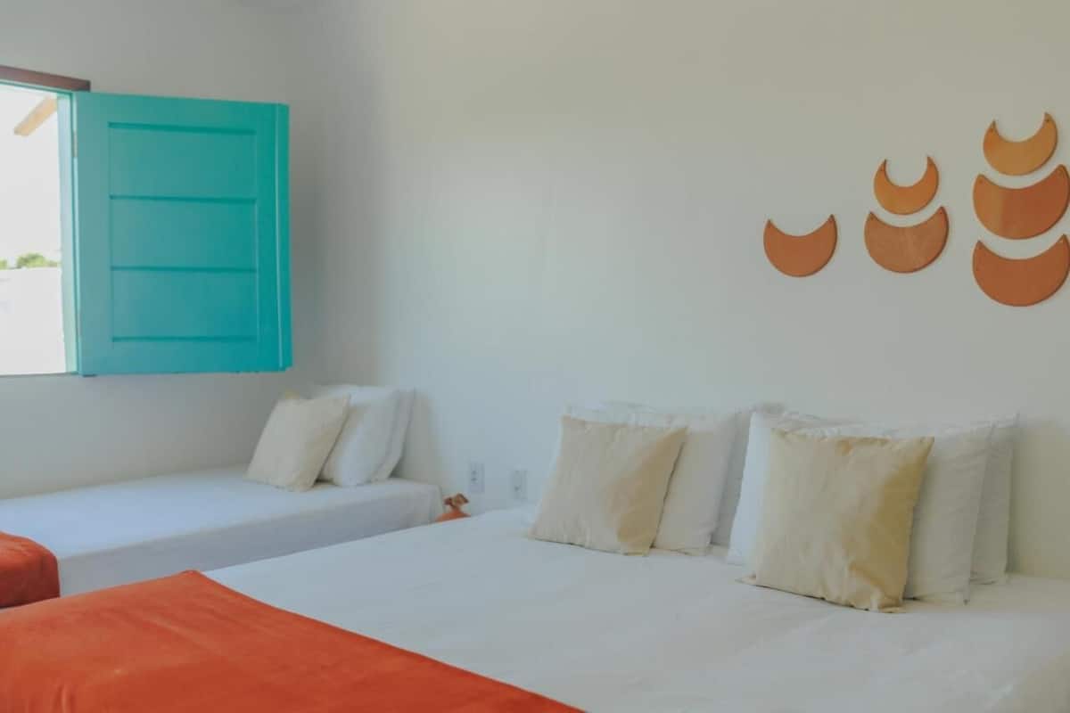 Una habitación con una cama, dos sofás blancos, un armario azul turquesa y una pared decorada con adornos de luna creciente.