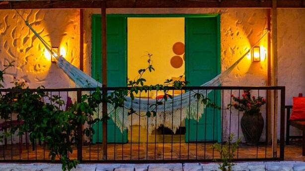A room with a hammock, a green door, and a wall with a textured pattern. - Quintal de Areias (Santo Amaro do Maranhão)