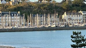 A marina with numerous sailboats docked, a stone wall separating the water from the shore, and residential buildings in the background. - Large character house (Binic-Étables-sur-Mer)