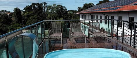 A swimming pool with a glass barrier, surrounded by wooden decking and metal railings.