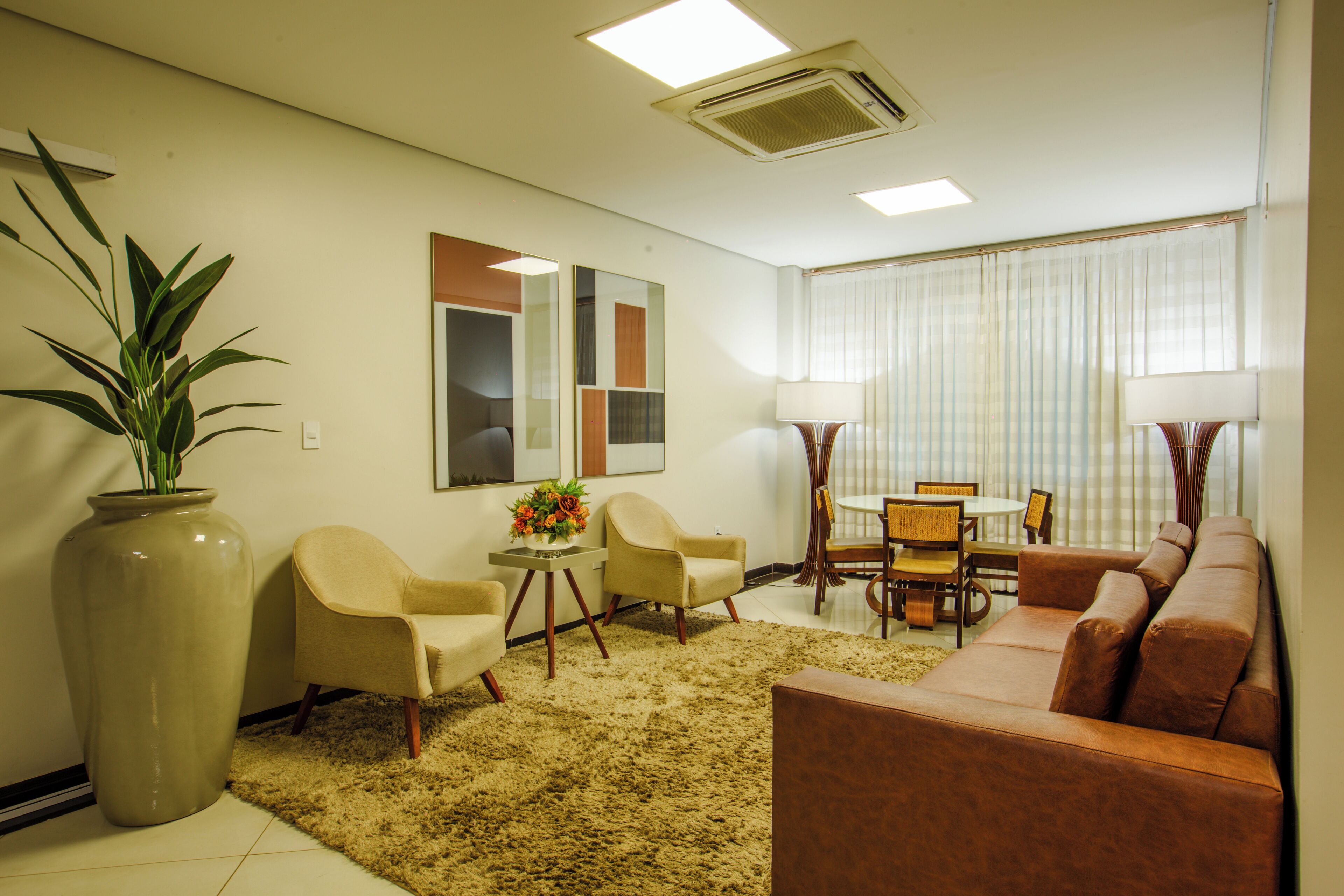 A living room with a sofa, chairs, a table, and a large plant.
