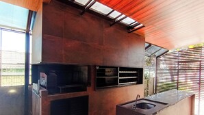 A modern kitchen with a built-in oven, a sink, and a window overlooking a garden. - Rede Andrade Rio Branco (Rio Branco)