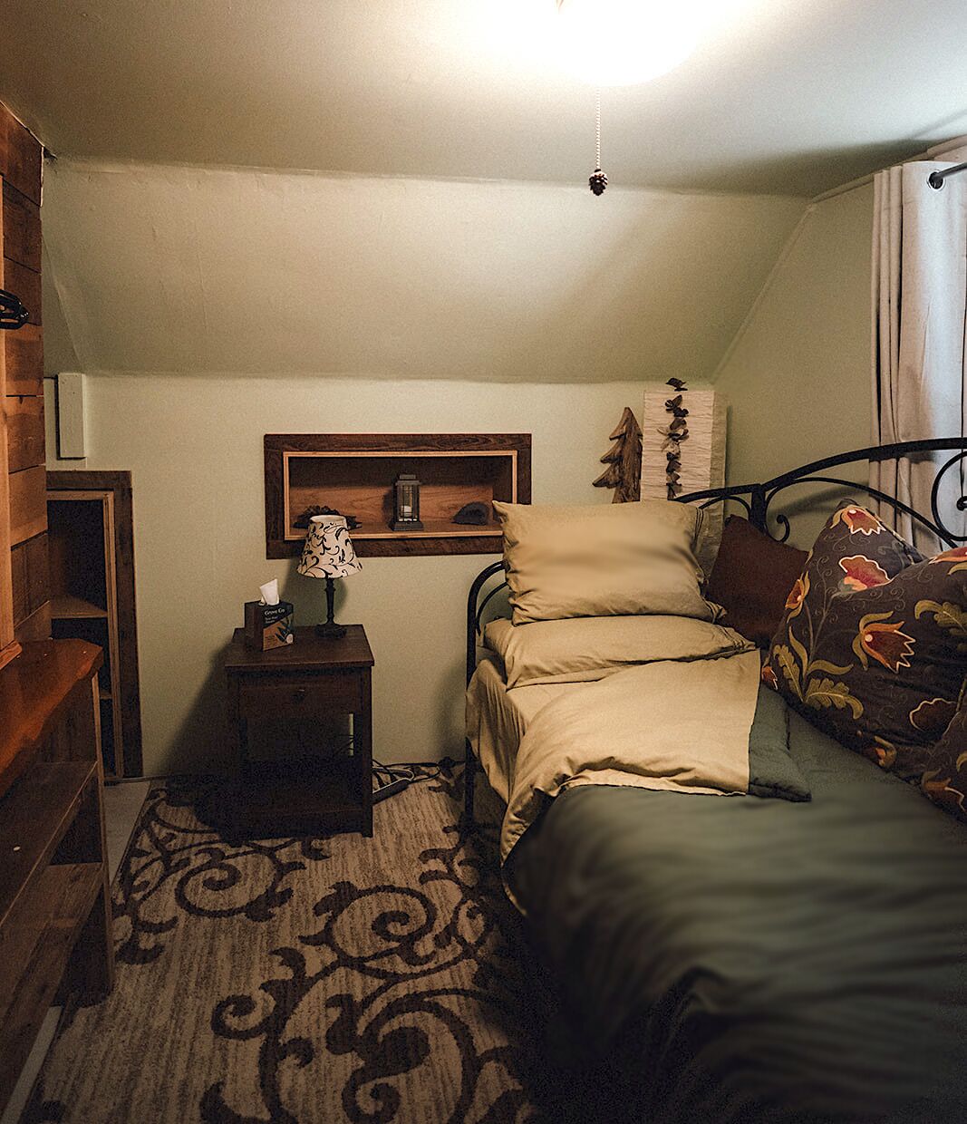 Ein Schlafzimmer mit Bett, Nachttisch, Lampe und einer Wandablage.