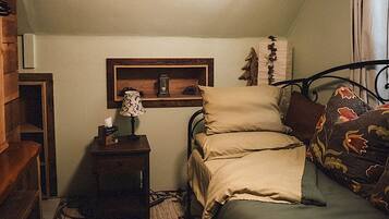 Ein Schlafzimmer mit Bett, Nachttisch, Lampe und einer Wandablage.