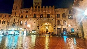 Un edificio histórico con una gran entrada arqueada, muros de piedra y un patio con suelo húmedo.