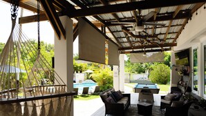 Un área de patio techada con mobiliario exterior, piscina y mesa de billar.