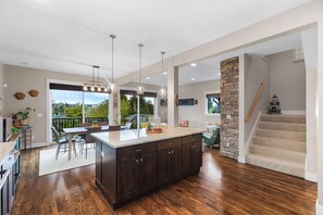 A spacious kitchen with dark wood cabinets, a large island, and pendant lighting. - Madrona Bliss A Modern Escape (Seattle)