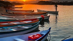 A serene lakeside scene with several boats docked at the shore. - Casa de Frente pro Mar com Piscina (Palhoca)