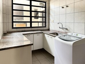 A compact kitchen with a built-in dishwasher, a sink, and a window with a view of the outside. - Casa de Frente pro Mar com Piscina (Palhoca)