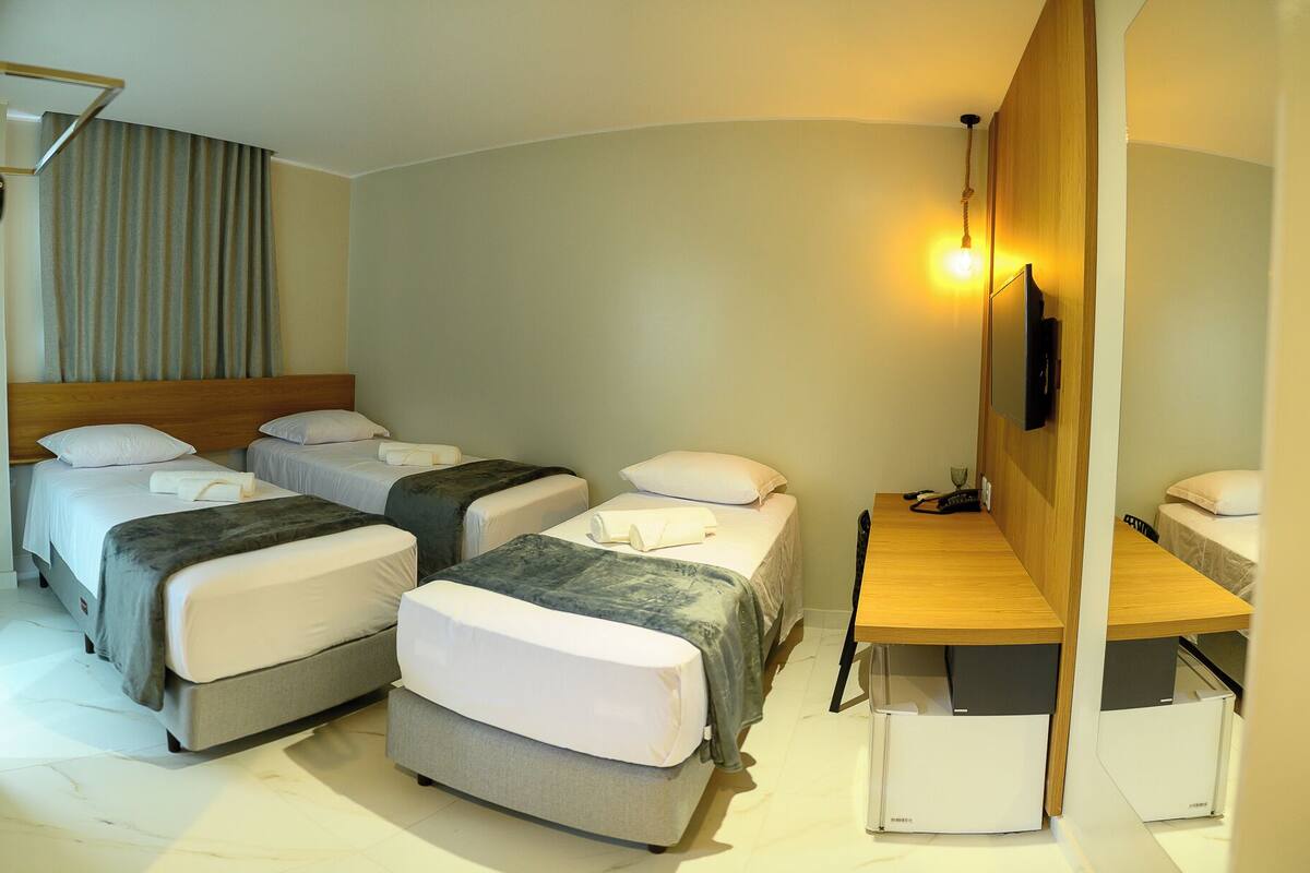 A hotel room with two single beds, a desk, and a chair.