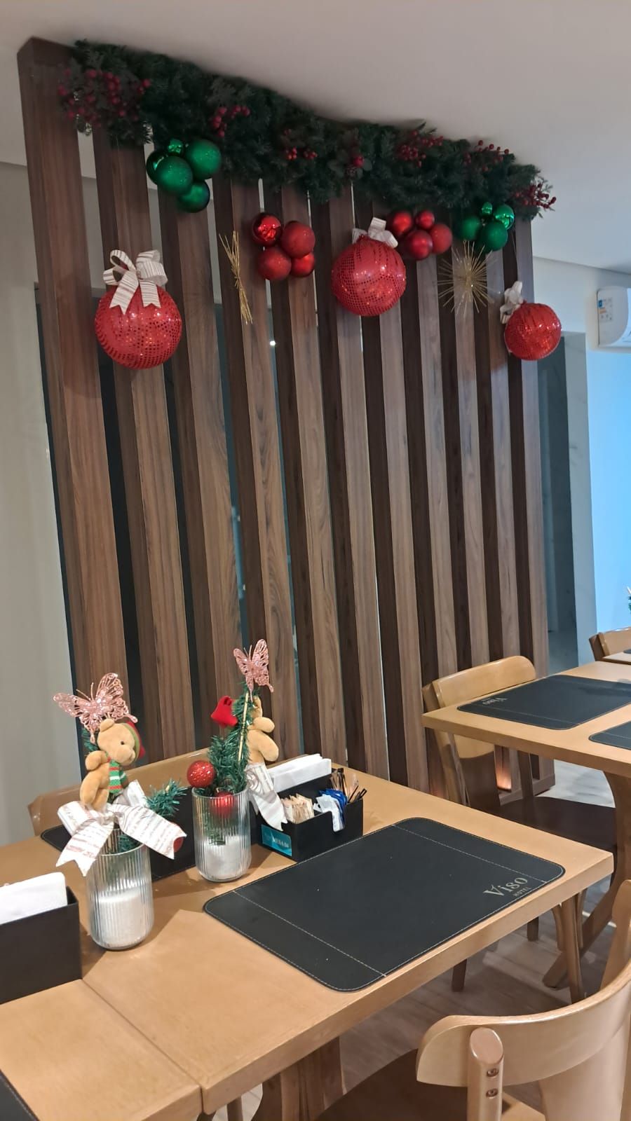 Ein Essbereich mit Holzhakobelwänden, roten und grünen Weihnachtsornamenten und einer Teddybäre-Dekoration.