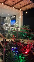 Una escalera con barandillas de metal y una baranda de vidrio, rodeada de exuberante vegetación y luces decorativas.