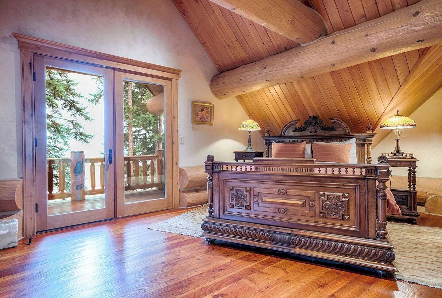 Um quarto espaçoso com uma cama de madeira grande, uma varanda com guarda-corpo de madeira e teto de madeira.