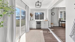 Una cocina moderna con gabinetes blancos, lavavajillas integrado y un amplio ventanal.