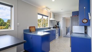 A modern kitchen with blue cabinets, a central island, and a view of the outdoors.