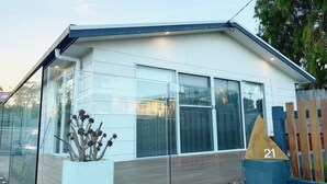 A modern building with large windows, a flat roof, and a number 21 sign. - Bodhi's Reef | Coastal Retreat (Lake Tyers Beach)