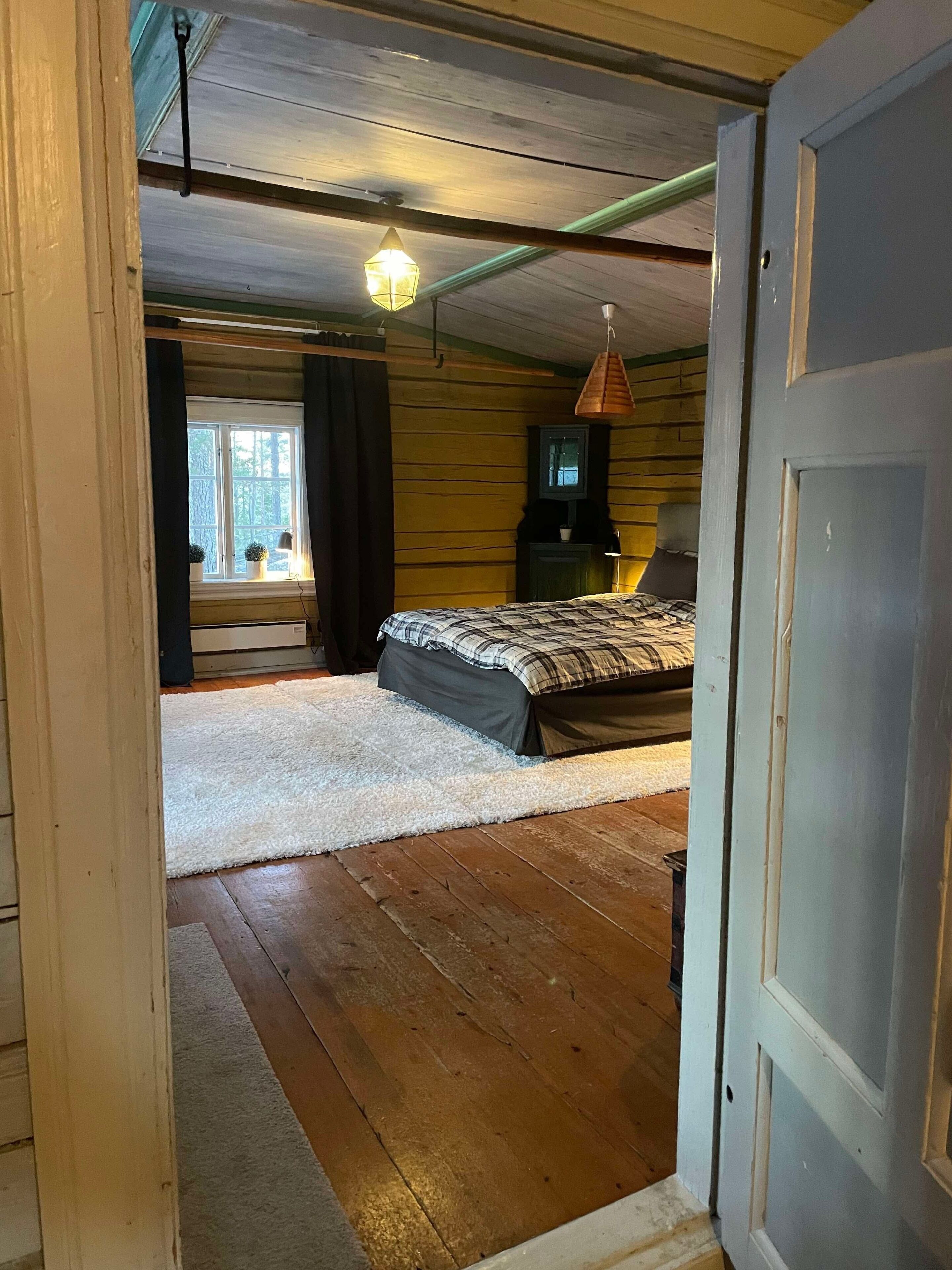 Une chambre à coucher avec un lit, une télévision et une fenêtre avec des rideaux.