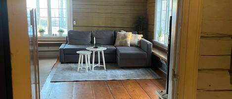 A cozy living room with a sectional sofa, a small table, and a ceiling fan.