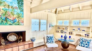 Una sala de estar acogedora con chimenea, asientos cómodos y vista al mar a través de amplios ventanales.