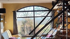 A spacious living area with a large window, a staircase, and a sofa.