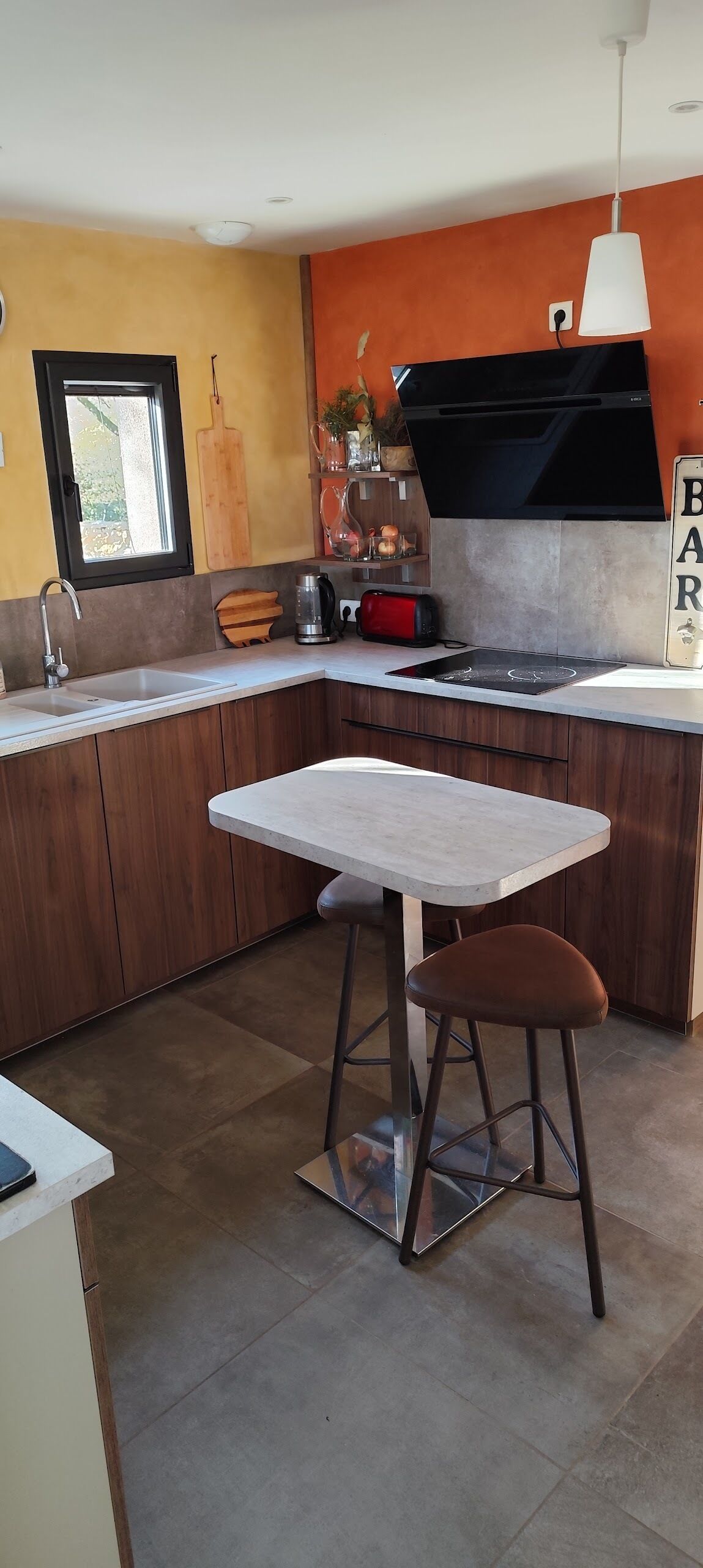 Una cocina moderna con horno integrado, un fregadero y un comedor con mesa y taburetes.