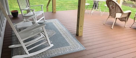 A wooden deck with a rocking chair, a small table, and chairs.