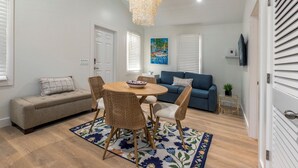 Un coin repas avec une table ronde, des chaises en osier, un tapis à motifs floraux et un lustre.