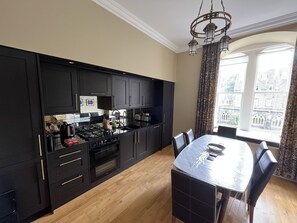 A modern kitchen with dark cabinetry, a central island, and a dining area with a table and chairs.