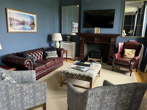 A living room with a fireplace, a television mounted above it, and a large mirror on the wall.