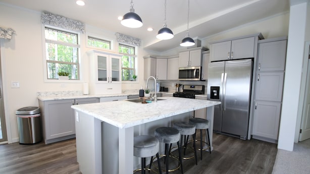 A modern kitchen with a central island, stainless steel appliances, and a large window.