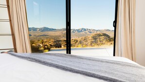 A bedroom with a large window offering a view of a mountainous landscape. - Rocky Roost: Cowboy Tub, Hot Tub, AC & Stargazing (Yucca Valley)