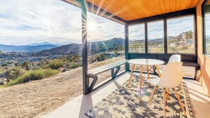 A modern room with large windows offering a view of a desert landscape and mountains. - Rocky Roost: Cowboy Tub, Hot Tub, AC & Stargazing (Yucca Valley)