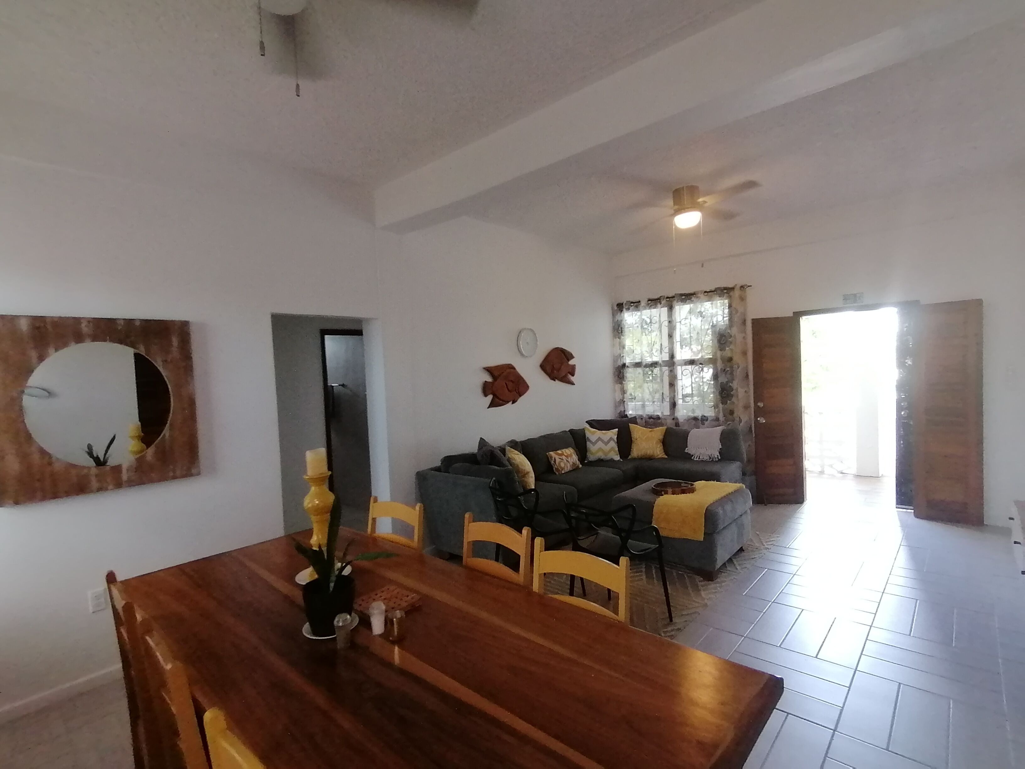 Un salón amplio con mesa de comedor, un conjunto de sofás y un ventilador de techo.