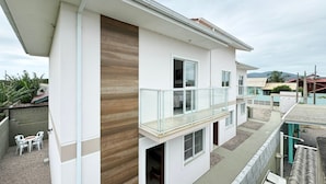 Een modern gebouw met twee verdiepingen, een balkon, houten accenten en uitzicht op de omgeving.