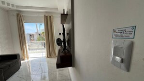A hotel lobby with a sofa, a fan, a sign, and a door with a security panel. - Condomínio com Piscina á 500m da Praia (Porto Seguro)