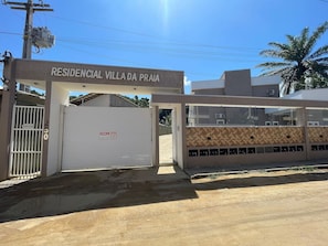 Une entrée fermée par un portail mène à une villa résidentielle, sur laquelle on peut lire l’inscription « RESIDENCIAL VILLA DA PRAIA ».