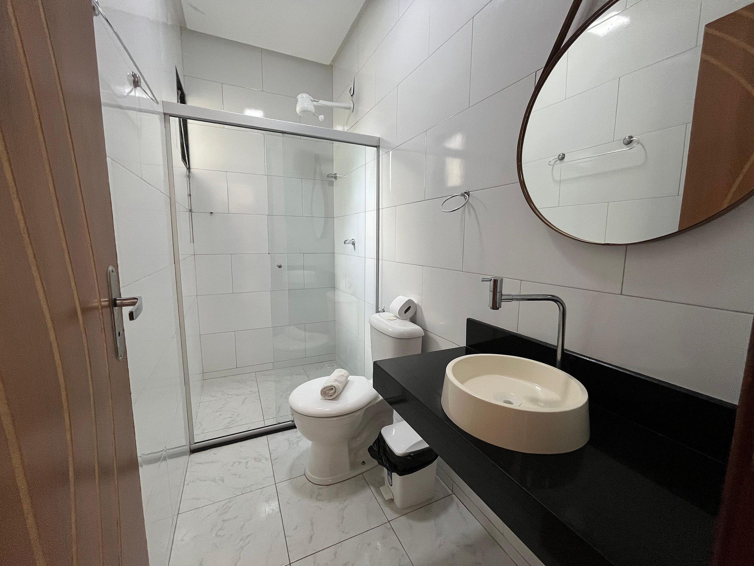 A modern bathroom with a glass-enclosed shower, a toilet, and a sink with a black countertop.