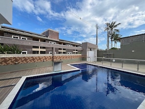 Una piscina con cubierta de madera, rodeada de edificios con diseño de mosaico de espiga y fachada de piedra.