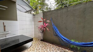 A tiled patio with a hammock, a grill, and a potted plant. - Condomínio com Piscina á 500m da Praia (Porto Seguro)